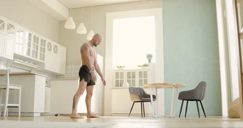 Athletic man in shorts is practicing handstand in kitchen at home, side view. Stock Footage 130160370