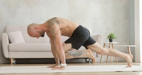 Athletic man in shorts is training and doing dynamic exercises in plank at home. Stock Footage 129904512
