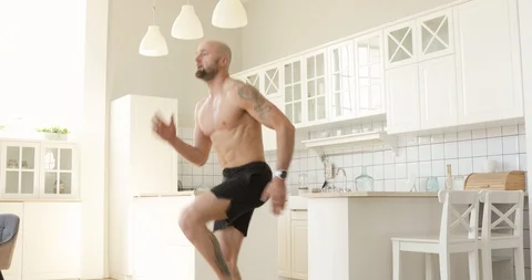 Athletic man in shorts is training and running in place on kitchen at home. Stock Footage 130159910
