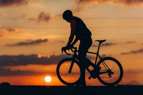Athletic man in silhouette posing on camera with bike Stock Photos
