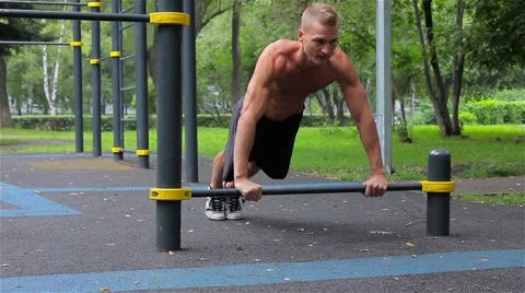 Athletic man slowly pushed off the crossbar in City Park. Workout Stock Footage 66420729