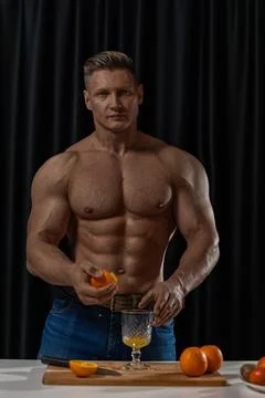 Athletic man squeezing fresh oranges in a kitchen setting for a healthy beverage Stock Photos