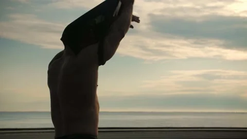  Athletic man stands looking off into the sunset, then takes off his T-shirt Stock Footage 200116583