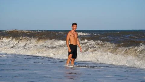 Athletic man in surf waves on the beach 스톡 사진