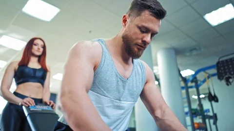 Athletic man takes two dumbbells in his hands and starts lifting them in gym. Stock Footage 111413739