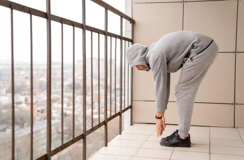 Athletic man in training clothes performs an exercise on his feet on the balc Stock Photos