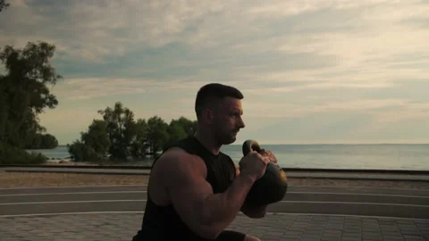 Аthletic man is training outdoors doing a squat with weights.Slow Motion Stockbeeldmateriaal 200116877