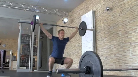 Athletic man training squats with barbells over head Stock Footage 112672329