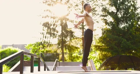 Athletic man training yoga poses outdoors.Guy balancing on tiptoe on yoga mat Stock Footage 158182088