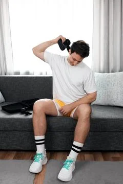 Athletic man using a massage gun on his neck for muscle relief. Post-workou.. Stock Photos