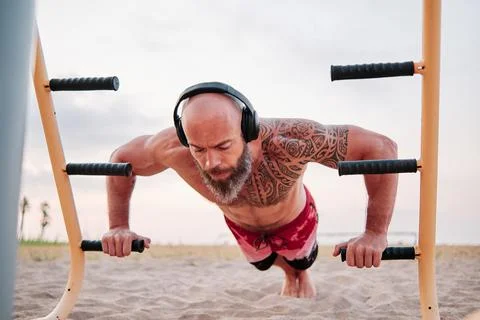 Athletic man using parallel bars to do push-ups while training calisthenics at Foto stock