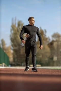 Athletic man walking through the stadium with victory cup Stock Photos