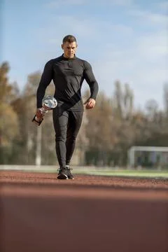 Athletic man walking through the stadium with victory cup Stock Photos