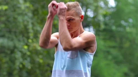 Athletic man warming up before exercise in City Park under summer trees for 스톡 동영상 66420621