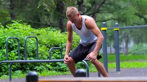 Athletic man warming up before exercise in City Park under summer trees for Video stock 66420624