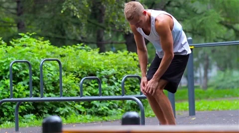 Athletic man warming up before exercise in City Park under summer trees for Stock Footage 66420636