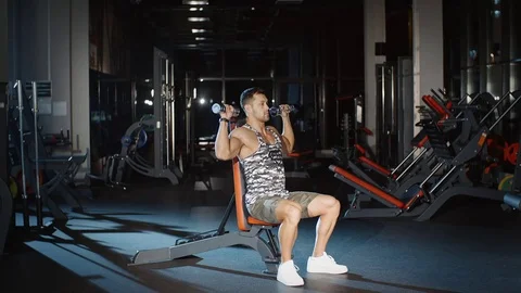Athletic man working on his abs biceps with dumbbells on a bench Stock Footage 81402999