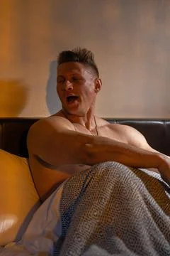 Athletic man yawns while relaxing in bed during morning hours at home Stock Photos