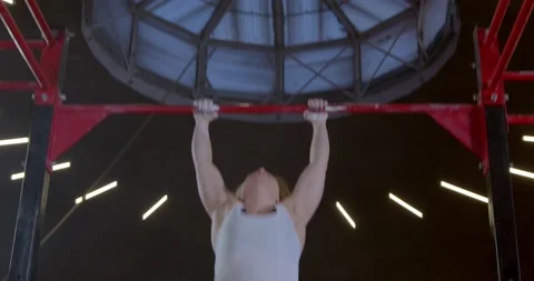 Athletic mature woman doing a pull-up an upper-body strength exercise modern gym Stock Footage 148226856