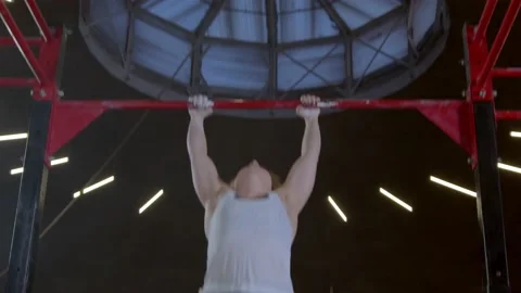 Athletic mature woman doing a pull-up an upper-body strength exercise modern gym Stock Footage 148331150