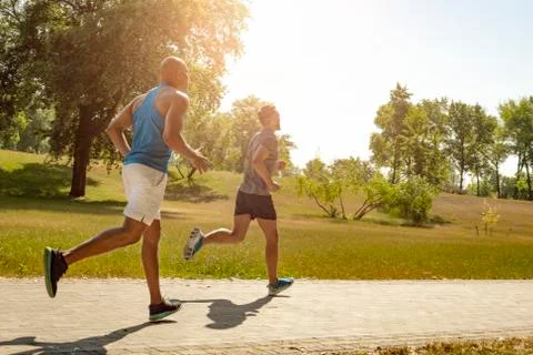 Athletic men jogging in the park. Stock Photos