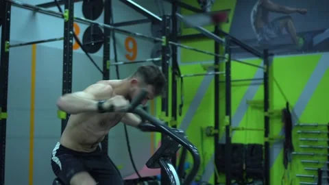 Athletic middle aged man training on air resistance bike. Side view Stock Footage 131029428