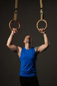 Athletic middle aged man training with rings, studio background Stock Photos