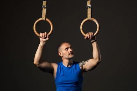 Athletic middle aged man training with rings, studio background Stock Photos