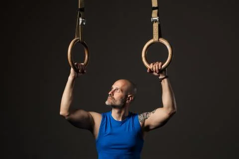Athletic middle aged man training with rings, studio background Stock Photos