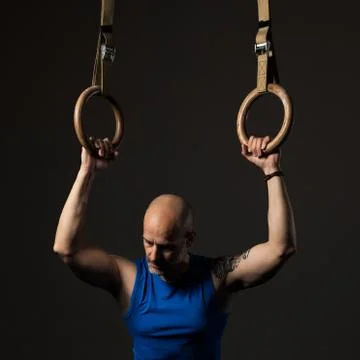 Athletic middle aged man training with rings, studio background Stock Photos