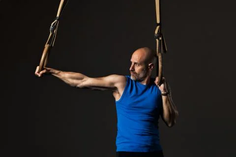 Athletic middle aged man training with rings, studio background 写真素材