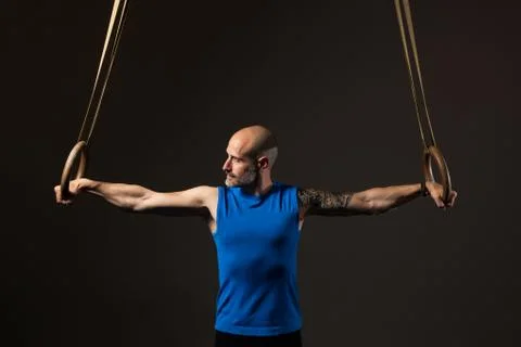 Athletic middle aged man training with rings, studio background 写真素材