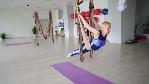 Athletic middle-aged woman doing aerial yoga in hammock indoors in superman pose Stock Footage 271276981