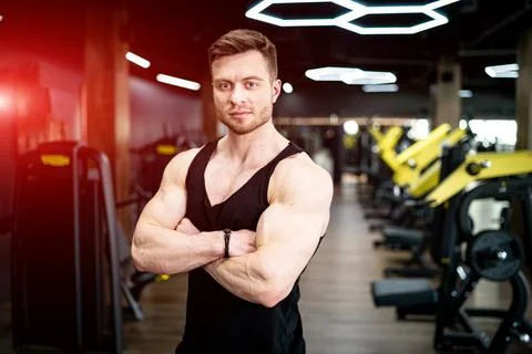 Athletic muscular man posing for camera. Bodybuilding trainer in the gym. Stock Photos