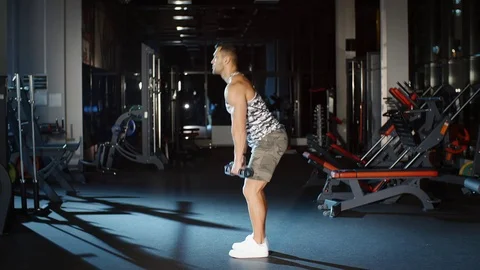 Athletic muscular man works out and sit up with dumbbells in gym Stock Footage