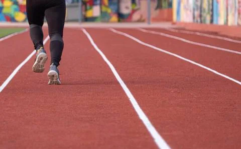An athletic pair of legs going for a run on a running track Stock Photos