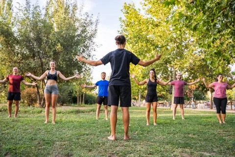 Athletic people practicing yoga on a sports class in nature. Stock Photos