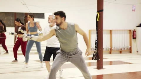Athletic people train in a fencing class, they confidently hold a rapier in Stock Footage 344776593