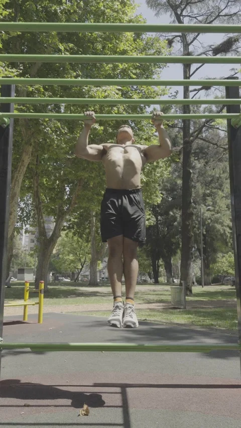 Athletic shirtless man with a strong physique doing pull-ups on parallel bars. Stock-Footage 326683587