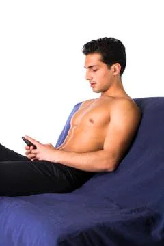 Athletic shirtless young man using cell phone to type text message Stock Photos
