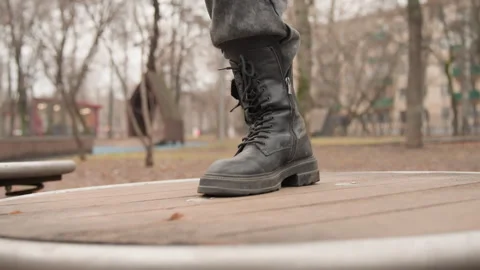 Athletic shoes backdrop. Dark boots on park platform. Weathered combat footwear Stock Footage 337370490