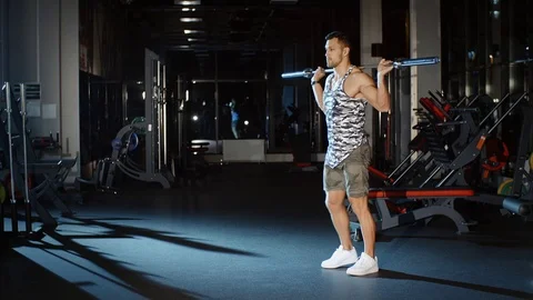Athletic sportsman trains his legs with barbell weight in gym Stock Footage