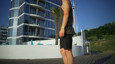 Athletic strong man pistol squats exercise seaside sunny pier rapid slow motion Stock Footage