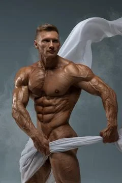Athletic strong man posing in a studio white cloth in an original way Stock Photos