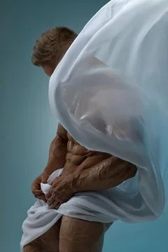 Athletic strong man posing in a studio white cloth in an original way Stock Photos