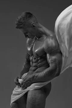 Athletic strong man posing in a studio white cloth in an original way Stock Photos