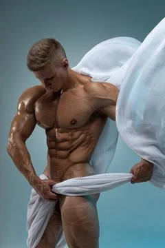 Athletic strong man posing in a studio white cloth in an original way Stock Photos