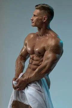 Athletic strong man posing in a studio white cloth in an original way Stock Photos