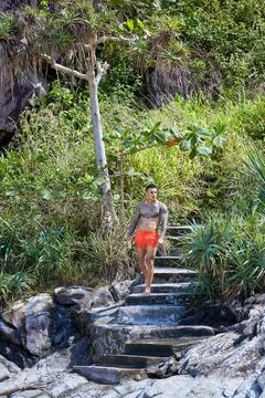 Athletic tattooed guy posing on staits at the jungles Stock Photos