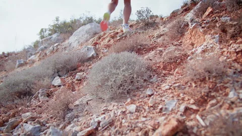 Athletic training man, wearing athletic shoes, climbing up a scorched mountain Stock Footage 312762695